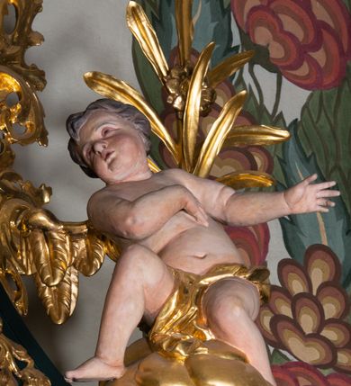 Zdjęcie nr 24: Nastawa architektoniczna, trójosiowa, dwukondygnacyjna, ustawiona na wysokim cokole z wyodrębnionymi prostopadłościanami. Ołtarz prostopadłościenny, z drewnianą mensą. Antepedium ujęte profilowaną ramą, w polu medalion z monogramem IHS w glorii. Na ołtarzu ustawione tabernakulum z tronem wystawienia. Tabernakulum w formie trójosiowej skrzynki, o wklęsło-wypukłym licu, artykułowanej kolumienkami o kręconych trzonach, podtrzymującymi belkowanie, wyłamane na ich osi, z gzymsem wyłamanym faliście na osi środkowej. Drzwiczki w formie stojącego prostokąta zamkniętego łukiem półkolistym nadwieszonym z uskokiem, ujętego ramą z płaskorzeźbionym przedstawieniem kielicha z hostią w glorii. Na osiach bocznych płaskorzeźbione przedstawienia winnego grona. Tron wystawienia w formie paludamentu, podwójnie podwieszonego po bokach, zwieńczonego koroną zamkniętą. 
Cokół dekorowany płycinami wypełnionymi suchym akantem. Pierwsza kondygnacja nastawy ujęta dwiema parami kolumn o kapitelach kompozytowych oraz stojącą między nimi parą pilastrów, w których trzonach znajdują się gabloty na wota. Przed pilastrami na cokołach ustawione dwie figury aniołów. Podpory dźwigają pełne belkowanie, przerwane w partii architrawu i fryzu nad polem środkowym, wyłamane na osi kolumn, na osi pilastrów belkowanie wyłamane pod kątem, w formie impostu z podwieszonymi szyszkami. Na belkowaniu, na obłokach dwie figurki adorujących puttów oraz dwa wazony na cokołach. W polu środkowym wnęka w formie stojącego prostokąta o wciętych górnych narożach, ujęta podwójną ramą, dekorowaną ornamentem roślinnym, z obrazem św. Józefa. Wnęka otoczona z trzech stron gablotami z wotami. Nad nią, w polu belkowania kartusz utworzony z suchego akantu z napisem w polu: „ŚW(IĘTY) JÓZEFIE / MÓDL SIĘ / ZA NAMI”. Druga kondygnacja o szerokości osi środkowej, ustawiona na cokole z wyodrębnionymi prostopadłościanami oraz gablotą z wotami, ujęta dwiema parami pilastrów i spływami wolutowymi oraz stojącą przed nimi parą kolumn, dźwigających zdwojone imposty oraz fragmenty przerwanego, półkolistego przyczółka z siedzącymi puttami. Spływy zdobione festonami utworzonymi z wstęgi oraz kwiatów. Całość zamknięta fragmentem falistego gzymsu oraz Okiem Opatrzności w glorii promienistej. W polu obraz Zaślubin Marii ze św. Józefem w formie stojącego prostokąta o ściętych narożach, ujęty ramą dekorowaną ornamentem roślinnym. Flankowany dwiema prostokątnymi płycinami wypełnionymi akantem. Obie kondygnacje ujęte uszami utworzonymi z suchego akantu. Struktura polichromowana w kolorze zielonym, kolumny, ornamentyka i profile złocone.




