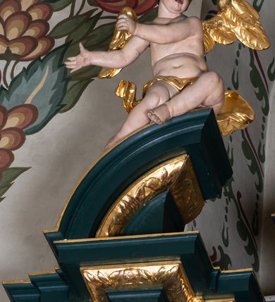 Zdjęcie nr 29: Nastawa architektoniczna, trójosiowa, dwukondygnacyjna, ustawiona na wysokim cokole z wyodrębnionymi prostopadłościanami. Ołtarz prostopadłościenny, z drewnianą mensą. Antepedium ujęte profilowaną ramą, w polu medalion z monogramem IHS w glorii. Na ołtarzu ustawione tabernakulum z tronem wystawienia. Tabernakulum w formie trójosiowej skrzynki, o wklęsło-wypukłym licu, artykułowanej kolumienkami o kręconych trzonach, podtrzymującymi belkowanie, wyłamane na ich osi, z gzymsem wyłamanym faliście na osi środkowej. Drzwiczki w formie stojącego prostokąta zamkniętego łukiem półkolistym nadwieszonym z uskokiem, ujętego ramą z płaskorzeźbionym przedstawieniem kielicha z hostią w glorii. Na osiach bocznych płaskorzeźbione przedstawienia winnego grona. Tron wystawienia w formie paludamentu, podwójnie podwieszonego po bokach, zwieńczonego koroną zamkniętą. 
Cokół dekorowany płycinami wypełnionymi suchym akantem. Pierwsza kondygnacja nastawy ujęta dwiema parami kolumn o kapitelach kompozytowych oraz stojącą między nimi parą pilastrów, w których trzonach znajdują się gabloty na wota. Przed pilastrami na cokołach ustawione dwie figury aniołów. Podpory dźwigają pełne belkowanie, przerwane w partii architrawu i fryzu nad polem środkowym, wyłamane na osi kolumn, na osi pilastrów belkowanie wyłamane pod kątem, w formie impostu z podwieszonymi szyszkami. Na belkowaniu, na obłokach dwie figurki adorujących puttów oraz dwa wazony na cokołach. W polu środkowym wnęka w formie stojącego prostokąta o wciętych górnych narożach, ujęta podwójną ramą, dekorowaną ornamentem roślinnym, z obrazem św. Józefa. Wnęka otoczona z trzech stron gablotami z wotami. Nad nią, w polu belkowania kartusz utworzony z suchego akantu z napisem w polu: „ŚW(IĘTY) JÓZEFIE / MÓDL SIĘ / ZA NAMI”. Druga kondygnacja o szerokości osi środkowej, ustawiona na cokole z wyodrębnionymi prostopadłościanami oraz gablotą z wotami, ujęta dwiema parami pilastrów i spływami wolutowymi oraz stojącą przed nimi parą kolumn, dźwigających zdwojone imposty oraz fragmenty przerwanego, półkolistego przyczółka z siedzącymi puttami. Spływy zdobione festonami utworzonymi z wstęgi oraz kwiatów. Całość zamknięta fragmentem falistego gzymsu oraz Okiem Opatrzności w glorii promienistej. W polu obraz Zaślubin Marii ze św. Józefem w formie stojącego prostokąta o ściętych narożach, ujęty ramą dekorowaną ornamentem roślinnym. Flankowany dwiema prostokątnymi płycinami wypełnionymi akantem. Obie kondygnacje ujęte uszami utworzonymi z suchego akantu. Struktura polichromowana w kolorze zielonym, kolumny, ornamentyka i profile złocone.




