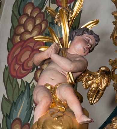 Zdjęcie nr 26: Nastawa architektoniczna, trójosiowa, dwukondygnacyjna, ustawiona na wysokim cokole z wyodrębnionymi prostopadłościanami. Ołtarz prostopadłościenny, z drewnianą mensą. Antepedium ujęte profilowaną ramą, w polu medalion z monogramem IHS w glorii. Na ołtarzu ustawione tabernakulum z tronem wystawienia. Tabernakulum w formie trójosiowej skrzynki, o wklęsło-wypukłym licu, artykułowanej kolumienkami o kręconych trzonach, podtrzymującymi belkowanie, wyłamane na ich osi, z gzymsem wyłamanym faliście na osi środkowej. Drzwiczki w formie stojącego prostokąta zamkniętego łukiem półkolistym nadwieszonym z uskokiem, ujętego ramą z płaskorzeźbionym przedstawieniem kielicha z hostią w glorii. Na osiach bocznych płaskorzeźbione przedstawienia winnego grona. Tron wystawienia w formie paludamentu, podwójnie podwieszonego po bokach, zwieńczonego koroną zamkniętą. 
Cokół dekorowany płycinami wypełnionymi suchym akantem. Pierwsza kondygnacja nastawy ujęta dwiema parami kolumn o kapitelach kompozytowych oraz stojącą między nimi parą pilastrów, w których trzonach znajdują się gabloty na wota. Przed pilastrami na cokołach ustawione dwie figury aniołów. Podpory dźwigają pełne belkowanie, przerwane w partii architrawu i fryzu nad polem środkowym, wyłamane na osi kolumn, na osi pilastrów belkowanie wyłamane pod kątem, w formie impostu z podwieszonymi szyszkami. Na belkowaniu, na obłokach dwie figurki adorujących puttów oraz dwa wazony na cokołach. W polu środkowym wnęka w formie stojącego prostokąta o wciętych górnych narożach, ujęta podwójną ramą, dekorowaną ornamentem roślinnym, z obrazem św. Józefa. Wnęka otoczona z trzech stron gablotami z wotami. Nad nią, w polu belkowania kartusz utworzony z suchego akantu z napisem w polu: „ŚW(IĘTY) JÓZEFIE / MÓDL SIĘ / ZA NAMI”. Druga kondygnacja o szerokości osi środkowej, ustawiona na cokole z wyodrębnionymi prostopadłościanami oraz gablotą z wotami, ujęta dwiema parami pilastrów i spływami wolutowymi oraz stojącą przed nimi parą kolumn, dźwigających zdwojone imposty oraz fragmenty przerwanego, półkolistego przyczółka z siedzącymi puttami. Spływy zdobione festonami utworzonymi z wstęgi oraz kwiatów. Całość zamknięta fragmentem falistego gzymsu oraz Okiem Opatrzności w glorii promienistej. W polu obraz Zaślubin Marii ze św. Józefem w formie stojącego prostokąta o ściętych narożach, ujęty ramą dekorowaną ornamentem roślinnym. Flankowany dwiema prostokątnymi płycinami wypełnionymi akantem. Obie kondygnacje ujęte uszami utworzonymi z suchego akantu. Struktura polichromowana w kolorze zielonym, kolumny, ornamentyka i profile złocone.





