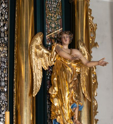 Zdjęcie nr 31: Nastawa architektoniczna, trójosiowa, dwukondygnacyjna, ustawiona na wysokim cokole z wyodrębnionymi prostopadłościanami. Ołtarz prostopadłościenny, z drewnianą mensą. Antepedium ujęte profilowaną ramą, w polu medalion z monogramem IHS w glorii. Na ołtarzu ustawione tabernakulum z tronem wystawienia. Tabernakulum w formie trójosiowej skrzynki, o wklęsło-wypukłym licu, artykułowanej kolumienkami o kręconych trzonach, podtrzymującymi belkowanie, wyłamane na ich osi, z gzymsem wyłamanym faliście na osi środkowej. Drzwiczki w formie stojącego prostokąta zamkniętego łukiem półkolistym nadwieszonym z uskokiem, ujętego ramą z płaskorzeźbionym przedstawieniem kielicha z hostią w glorii. Na osiach bocznych płaskorzeźbione przedstawienia winnego grona. Tron wystawienia w formie paludamentu, podwójnie podwieszonego po bokach, zwieńczonego koroną zamkniętą. 
Cokół dekorowany płycinami wypełnionymi suchym akantem. Pierwsza kondygnacja nastawy ujęta dwiema parami kolumn o kapitelach kompozytowych oraz stojącą między nimi parą pilastrów, w których trzonach znajdują się gabloty na wota. Przed pilastrami na cokołach ustawione dwie figury aniołów. Podpory dźwigają pełne belkowanie, przerwane w partii architrawu i fryzu nad polem środkowym, wyłamane na osi kolumn, na osi pilastrów belkowanie wyłamane pod kątem, w formie impostu z podwieszonymi szyszkami. Na belkowaniu, na obłokach dwie figurki adorujących puttów oraz dwa wazony na cokołach. W polu środkowym wnęka w formie stojącego prostokąta o wciętych górnych narożach, ujęta podwójną ramą, dekorowaną ornamentem roślinnym, z obrazem św. Józefa. Wnęka otoczona z trzech stron gablotami z wotami. Nad nią, w polu belkowania kartusz utworzony z suchego akantu z napisem w polu: „ŚW(IĘTY) JÓZEFIE / MÓDL SIĘ / ZA NAMI”. Druga kondygnacja o szerokości osi środkowej, ustawiona na cokole z wyodrębnionymi prostopadłościanami oraz gablotą z wotami, ujęta dwiema parami pilastrów i spływami wolutowymi oraz stojącą przed nimi parą kolumn, dźwigających zdwojone imposty oraz fragmenty przerwanego, półkolistego przyczółka z siedzącymi puttami. Spływy zdobione festonami utworzonymi z wstęgi oraz kwiatów. Całość zamknięta fragmentem falistego gzymsu oraz Okiem Opatrzności w glorii promienistej. W polu obraz Zaślubin Marii ze św. Józefem w formie stojącego prostokąta o ściętych narożach, ujęty ramą dekorowaną ornamentem roślinnym. Flankowany dwiema prostokątnymi płycinami wypełnionymi akantem. Obie kondygnacje ujęte uszami utworzonymi z suchego akantu. Struktura polichromowana w kolorze zielonym, kolumny, ornamentyka i profile złocone.




