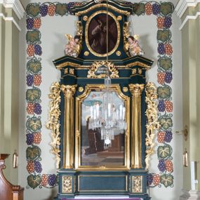 Zdjęcie nr 1: Nastawa architektoniczna, jednoosiowa, jednokondygnacyjna ze zwieńczeniem, ustawiona na dwustrefowym cokole z wyodrębnionymi dwoma prostopadłościanami. Ołtarz prostopadłościenny, z drewnianą mensą. Antepedium ujęte profilowaną, złoconą ramą, na tle fioletowego pola mandorla z chrystogramem Chi Rho oraz literami alfa i omega, w glorii promienistej. Cokół w górnej strefie dekorowany płycinami wypełnionymi akantem. Nastawa flankowana parą kolumn o kapitelach kompozytowych, dźwigających pełne belkowanie, wyłamane pod kątem na ich osi, z siedzącymi na nim puttami, o fryzie dekorowanym rozetami. Pole centralne niemal w całości wypełnione wnęką ujętą profilowaną ramą zdobioną miejscami ornamentem roślinnym, w formie stojącego prostokąta o wklęsłych górnych narożach. We wnęce obraz z przedstawieniem św. Antoniego Padewskiego, na zasuwie św. Elżbiety Węgierskiej. Nad obrazem, w polu belkowania kartusz utworzony z akantu, kampanuli i liści z napisem „S(ANC)T(E) ANTONI / ORA PRO NOBIS”. Kondygnacja ujęta uszami utworzonymi z akantu i kampanuli. Zwieńczenie w formie stojącego prostokąta o lekko wklęsłych bokach, zamknięte fragmentem falistego gzymsu, na którym siedzi putto i uskrzydlona główka anielska. W polu obraz Chrystusa dźwigającego krzyż w formie stojącego owalu, ujęty ramą zdobioną wieńcem laurowym. Zwieńczenie dekorowane w polu czterema rozetami, flankowane uszami z akantu. Struktura polichromowana w kolorze zielonym, ze złoconymi kolumnami, profilami i ornamentyką. 