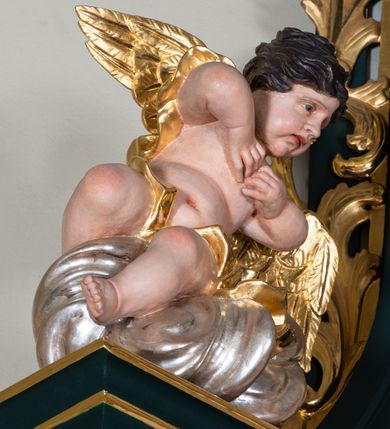 Zdjęcie nr 8: Nastawa architektoniczna, jednoosiowa, jednokondygnacyjna ze zwieńczeniem, ustawiona na dwustrefowym cokole z wyodrębnionymi dwoma prostopadłościanami. Ołtarz prostopadłościenny, z drewnianą mensą. Antepedium ujęte profilowaną, złoconą ramą, na tle fioletowego pola mandorla z chrystogramem Chi Rho oraz literami alfa i omega, w glorii promienistej. Cokół w górnej strefie dekorowany płycinami wypełnionymi akantem. Nastawa flankowana parą kolumn o kapitelach kompozytowych, dźwigających pełne belkowanie, wyłamane pod kątem na ich osi, z siedzącymi na nim puttami, o fryzie dekorowanym rozetami. Pole centralne niemal w całości wypełnione wnęką ujętą profilowaną ramą zdobioną miejscami ornamentem roślinnym, w formie stojącego prostokąta o wklęsłych górnych narożach. We wnęce obraz z przedstawieniem św. Antoniego Padewskiego, na zasuwie św. Elżbiety Węgierskiej. Nad obrazem, w polu belkowania kartusz utworzony z akantu, kampanuli i liści z napisem „S(ANC)T(E) ANTONI / ORA PRO NOBIS”. Kondygnacja ujęta uszami utworzonymi z akantu i kampanuli. Zwieńczenie w formie stojącego prostokąta o lekko wklęsłych bokach, zamknięte fragmentem falistego gzymsu, na którym siedzi putto i uskrzydlona główka anielska. W polu obraz Chrystusa dźwigającego krzyż w formie stojącego owalu, ujęty ramą zdobioną wieńcem laurowym. Zwieńczenie dekorowane w polu czterema rozetami, flankowane uszami z akantu. Struktura polichromowana w kolorze zielonym, ze złoconymi kolumnami, profilami i ornamentyką. 