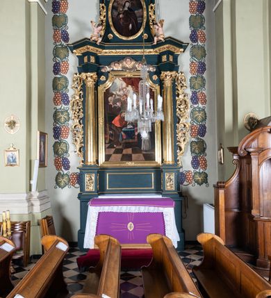 Zdjęcie nr 2: Nastawa architektoniczna, jednoosiowa, jednokondygnacyjna ze zwieńczeniem, ustawiona na dwustrefowym cokole z wyodrębnionymi dwoma prostopadłościanami. Ołtarz prostopadłościenny, z drewnianą mensą. Antepedium ujęte profilowaną, złoconą ramą, na tle fioletowego pola mandorla z chrystogramem Chi Rho oraz literami alfa i omega, w glorii promienistej. Cokół w górnej strefie dekorowany płycinami wypełnionymi akantem. Nastawa flankowana parą kolumn o kapitelach kompozytowych, dźwigających pełne belkowanie, wyłamane pod kątem na ich osi, przerwane pośrodku, z siedzącymi na nim puttami, o fryzie dekorowanym rozetami. Pole centralne niemal w całości wypełnione wnęką ujętą profilowaną ramą zdobioną miejscami  ornamentem roślinnym, w formie stojącego prostokąta o wklęsłych górnych narożach. We wnęce obraz z przedstawieniem św. Agnieszki, na zasuwie św. Bonawentury i św. Tomasza z Akwinu. Nad obrazem rzeźbione obłoki z trzema uskrzydlonymi główkami anielskimi. Kondygnacja ujęta uszami utworzonymi z akantu i kampanuli. Zwieńczenie w formie stojącego prostokąta o lekko wklęsłych bokach, zamknięte fragmentem falistego gzymsu, na którym siedzi putto. W polu obraz św. Klary w formie stojącego owalu, ujęty ramą zdobioną wieńcem laurowym. Zwieńczenie dekorowane w polu czterema rozetami, flankowane uszami z akantu. Struktura polichromowana w kolorze zielonym, ze złoconymi kolumnami, profilami i ornamentyką. 