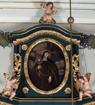 Zdjęcie nr 8: Nastawa architektoniczna, jednoosiowa, jednokondygnacyjna ze zwieńczeniem, ustawiona na dwustrefowym cokole z wyodrębnionymi dwoma prostopadłościanami. Ołtarz prostopadłościenny, z drewnianą mensą. Antepedium ujęte profilowaną, złoconą ramą, na tle fioletowego pola mandorla z chrystogramem Chi Rho oraz literami alfa i omega, w glorii promienistej. Cokół w górnej strefie dekorowany płycinami wypełnionymi akantem. Nastawa flankowana parą kolumn o kapitelach kompozytowych, dźwigających pełne belkowanie, wyłamane pod kątem na ich osi, przerwane pośrodku, z siedzącymi na nim puttami, o fryzie dekorowanym rozetami. Pole centralne niemal w całości wypełnione wnęką ujętą profilowaną ramą zdobioną miejscami  ornamentem roślinnym, w formie stojącego prostokąta o wklęsłych górnych narożach. We wnęce obraz z przedstawieniem św. Agnieszki, na zasuwie św. Bonawentury i św. Tomasza z Akwinu. Nad obrazem rzeźbione obłoki z trzema uskrzydlonymi główkami anielskimi. Kondygnacja ujęta uszami utworzonymi z akantu i kampanuli. Zwieńczenie w formie stojącego prostokąta o lekko wklęsłych bokach, zamknięte fragmentem falistego gzymsu, na którym siedzi putto. W polu obraz św. Klary w formie stojącego owalu, ujęty ramą zdobioną wieńcem laurowym. Zwieńczenie dekorowane w polu czterema rozetami, flankowane uszami z akantu. Struktura polichromowana w kolorze zielonym, ze złoconymi kolumnami, profilami i ornamentyką. 