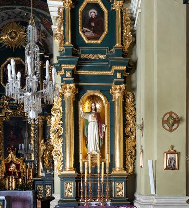 Zdjęcie nr 1: Nastawa architektoniczna, jednoosiowa, dwukondygnacyjna, ustawiona na cokole z wyodrębnionymi dwoma prostopadłościanami. Ołtarz prostopadłościenny, z drewnianą mensą. Antepedium ujęte profilowaną ramą, w polu medalion z monogramem IHS w glorii. Cokół dekorowany płycinami w partii wyodrębnionych prostopadłościanów wypełnionymi akantem. Pierwsza kondygnacja flankowana parą pilastrów i stojących przed nimi kolumn o kapitelach kompozytowych, dźwigających pełne belkowanie, wyłamane na ich osi, o fryzie dekorowanym rozetami. W polu centralnym nisza w formie stojącego prostokąta, zamkniętego łukiem półkolistym nadwieszonym, ujęta ramą zdobioną ornamentem roślinnym, z figurą Najświętszego Serca Jezusa. Druga kondygnacja ustawiona na cokole z wyodrębnionymi prostopadłościanami, flankowana parą pilastrów i stojących przed nimi kolumn o kapitelach kompozytowych, dźwigających imposty i fragmenty przerwanego, półkolistego przyczółka. Całość zamknięta fragmentem falistego gzymsu. W polu obraz św. Szymona z Lipnicy w formie stojącego prostokąta o ściętych narożach, ujętego ramą zdobioną ornamentem roślinnym. Obie kondygnacje z uszami utworzonymi ze stylizowanego akantu. Struktura polichromowana w kolorze zielonym, ze złoconymi kolumnami, profilami i ornamentyką. 