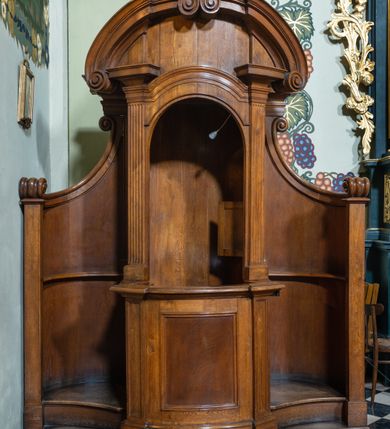 Zdjęcie nr 3: Konfesjonał na rzucie prostokąta z wklęsło-wypukłym frontem, lekko wklęsłymi zapleckami o ściankach ujętych spływami wolutowymi. Siedzisko z drzwiczkami lekko wybrzuszonymi, ujęte pilastrami z wybrzuszonym i profilowanym gzymsem oraz półkolistym przyczółkiem z dwiema stykającymi się wolutami.  