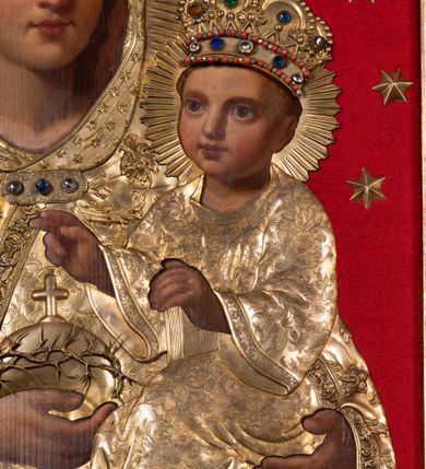 Zdjęcie nr 4: Obraz w kształcie stojącego prostokąta ujęty szeroką, akantową ramą z umieszczoną w górnej części, w osi obrazu, stylizowaną tarczą mieszczącą monogram maryjny. W centrum kompozycji przedstawiona Matka Boska z Dzieciątkiem. Maria ukazana frontalnie, w popiersiu. W prawej ręce Maria trzyma jabłko królewskie obwiedzione koroną cierniową i zwieńczone krzyżem, lewą ręką podtrzymuje Dzieciątko Jezus. Głowa Marii jest skierowana na wprost, owalna twarz ma regularne rysy. Oczy są duże, niebieskie, nos wydatny, prosty. Niewielkie usta zaznaczone są karminem. Wokół głowy Marii widnieje nimb promienisty oraz wieniec z 12 gwiazd, na głowie postaci znajduje się korona wysadzana kamieniami szlachetnymi, zwieńczona krzyżem. Postać jest ubrana w dekorowaną ornamentem roślinnym suknię oraz obszerny płaszcz z ciężkiej tkaniny dekorowanej motywami kwiatowymi, wykończony dodatkowo lamówką i spięty pod szyją ozdobną broszą. Głowa Marii okryta luźno udrapowaną wokół szyi chustą z motywem gwiazd. Dzieciątko ukazane całopostaciowo, w pozycji siedzącej, w trzech czwartych zwrócone w prawo. Prawą ręką błogosławi, lewą wspiera na księdze. Twarz Jezusa okrągła z wyraźnie zaznaczonym rumieńcem oraz dużymi, jasnymi oczami i prostym nosem. Wokół głowy ukazany nimb promienisty, a na głowie bogato wysadzana kamieniami szlachetnymi korona zwieńczona krzyżem. Dzieciątko ubrane w tunikę z długimi rękawami dekorowaną motywem roślinnym. Tło obrazu jest jednolicie czerwone, wyłożone aksamitną tkaniną. Na postaci Marii i Dzieciątka nałożono blaszane, złocone sukienki, odkrywające twarze oraz dłonie i stopy (w przypadku Jezusa) postaci.