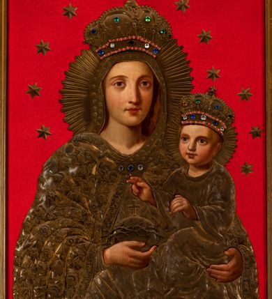 Zdjęcie nr 7: Obraz w kształcie stojącego prostokąta ujęty szeroką, akantową ramą z umieszczoną w górnej części, w osi obrazu, stylizowaną tarczą mieszczącą monogram maryjny. W centrum kompozycji przedstawiona Matka Boska z Dzieciątkiem. Maria ukazana frontalnie, w popiersiu. W prawej ręce Maria trzyma jabłko królewskie obwiedzione koroną cierniową i zwieńczone krzyżem, lewą ręką podtrzymuje Dzieciątko Jezus. Głowa Marii jest skierowana na wprost, owalna twarz ma regularne rysy. Oczy są duże, niebieskie, nos wydatny, prosty. Niewielkie usta zaznaczone są karminem. Wokół głowy Marii widnieje nimb promienisty oraz wieniec z 12 gwiazd, na głowie postaci znajduje się korona wysadzana kamieniami szlachetnymi, zwieńczona krzyżem. Postać jest ubrana w dekorowaną ornamentem roślinnym suknię oraz obszerny płaszcz z ciężkiej tkaniny dekorowanej motywami kwiatowymi, wykończony dodatkowo lamówką i spięty pod szyją ozdobną broszą. Głowa Marii okryta luźno udrapowaną wokół szyi chustą z motywem gwiazd. Dzieciątko ukazane całopostaciowo, w pozycji siedzącej, w trzech czwartych zwrócone w prawo. Prawą ręką błogosławi, lewą wspiera na księdze. Twarz Jezusa okrągła z wyraźnie zaznaczonym rumieńcem oraz dużymi, jasnymi oczami i prostym nosem. Wokół głowy ukazany nimb promienisty, a na głowie bogato wysadzana kamieniami szlachetnymi korona zwieńczona krzyżem. Dzieciątko ubrane w tunikę z długimi rękawami dekorowaną motywem roślinnym. Tło obrazu jest jednolicie czerwone, wyłożone aksamitną tkaniną. Na postaci Marii i Dzieciątka nałożono blaszane, złocone sukienki, odkrywające twarze oraz dłonie i stopy (w przypadku Jezusa) postaci.