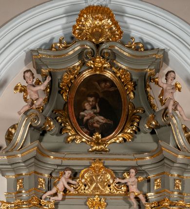Zdjęcie nr 13: Ołtarz jednoosiowy, jednokondygnacyjny ze zwieńczeniem. Podwójny cokół z wąską, drewnianą mensą ołtarzową, tabernakulum ze spływami wolutowymi. Retabulum flankowane dwiema ćwierć kolumnami skierowanymi po ukosie na zewnątrz, z których każda ujęta parą korynckich, kanelowanych pilastrów dźwigających przełamujące się nad nimi belkowanie i dwa faliste naczółki. Na tle pilastrów, na konsolach stoją dwa uskrzydlone anioły. Zwieńczenie ujęte spływami wolutowymi, zakończone dwiema profilowanym, lekko falistym gzymsem z dwiema stykającymi się wolutami. W polu głównym szeroka, złocona, prostokątna rama z obrazami „Św. Mikołaj” i "Wizja św. Franciszka" na zasuwie, w zwieńczeniu owalny obraz w złoconej ramie z przedstawieniem św. Antoniego. Figury aniołów wydrążone, ukazane w kontrapoście, z dłońmi wysuniętymi do przodu; anioł po lewej trzyma chustę. Ich twarze są owalne o regularnych rysach, z brązowymi puklowanymi włosami sięgającymi ramion. Z tyłu przymocowane duże, złote skrzydła. Ubrane są w długie, złote szaty o ostrym zarysie, odsłaniające klatkę piersiową i jedną z nóg. W partii belkowania para nagich puttów ze złoconymi opaskami na biodrach ujmujących kartusz w rokokowym obramieniu z chrystogramem. Na naczółkach z kolei siedzą nagie putta z przepaskami na biodrach i złotymi skrzydełkami. Na dekorację ornamentalną składają się drobne motywy roślinne, kampanule na ćwierćkolumnach, zwisy róż i gałązek wokół obrazu w zwieńczeniu i efektowna podwójna muszla palmetowa w zwieńczeniu. 
