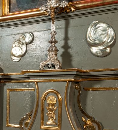 Zdjęcie nr 12: Ołtarz jednoosiowy, jednokondygnacyjny ze zwieńczeniem. Podwójny cokół z wąską, drewnianą mensą ołtarzową, tabernakulum ze spływami wolutowymi. Retabulum flankowane dwiema ćwierć kolumnami skierowanymi po ukosie na zewnątrz, z których każda ujęta parą korynckich, kanelowanych pilastrów dźwigających przełamujące się nad nimi belkowanie i dwa faliste naczółki. Na tle pilastrów, na konsolach stoją dwa uskrzydlone anioły. Zwieńczenie ujęte spływami wolutowymi, zakończone dwiema profilowanym, lekko falistym gzymsem z dwiema stykającymi się wolutami. W polu głównym szeroka, złocona, prostokątna rama z obrazami „Św. Mikołaj” i "Wizja św. Franciszka" na zasuwie, w zwieńczeniu owalny obraz w złoconej ramie z przedstawieniem św. Antoniego. Figury aniołów wydrążone, ukazane w kontrapoście, z dłońmi wysuniętymi do przodu; anioł po lewej trzyma chustę. Ich twarze są owalne o regularnych rysach, z brązowymi puklowanymi włosami sięgającymi ramion. Z tyłu przymocowane duże, złote skrzydła. Ubrane są w długie, złote szaty o ostrym zarysie, odsłaniające klatkę piersiową i jedną z nóg. W partii belkowania para nagich puttów ze złoconymi opaskami na biodrach ujmujących kartusz w rokokowym obramieniu z chrystogramem. Na naczółkach z kolei siedzą nagie putta z przepaskami na biodrach i złotymi skrzydełkami. Na dekorację ornamentalną składają się drobne motywy roślinne, kampanule na ćwierćkolumnach, zwisy róż i gałązek wokół obrazu w zwieńczeniu i efektowna podwójna muszla palmetowa w zwieńczeniu. 
