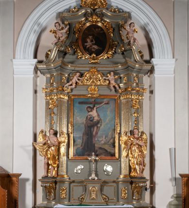 Zdjęcie nr 1: Ołtarz jednoosiowy, jednokondygnacyjny ze zwieńczeniem. Podwójny cokół z wąską, drewnianą mensą ołtarzową, tabernakulum ze spływami wolutowymi. Retabulum flankowane dwiema ćwierć kolumnami skierowanymi po ukosie na zewnątrz, z których każda ujęta parą korynckich, kanelowanych pilastrów dźwigających przełamujące się nad nimi belkowanie i dwa faliste naczółki. Na tle pilastrów, na konsolach stoją dwa uskrzydlone anioły. Zwieńczenie ujęte spływami wolutowymi, zakończone dwiema profilowanym, lekko falistym gzymsem z dwiema stykającymi się wolutami. W polu głównym szeroka, złocona, prostokątna rama z obrazami „Św. Mikołaj” i &quot;Wizja św. Franciszka&quot; na zasuwie, w zwieńczeniu owalny obraz w złoconej ramie z przedstawieniem św. Antoniego. Figury aniołów wydrążone, ukazane w kontrapoście, z dłońmi wysuniętymi do przodu; anioł po lewej trzyma chustę. Ich twarze są owalne o regularnych rysach, z brązowymi puklowanymi włosami sięgającymi ramion. Z tyłu przymocowane duże, złote skrzydła. Ubrane są w długie, złote szaty o ostrym zarysie, odsłaniające klatkę piersiową i jedną z nóg. W partii belkowania para nagich puttów ze złoconymi opaskami na biodrach ujmujących kartusz w rokokowym obramieniu z chrystogramem. Na naczółkach z kolei siedzą nagie putta z przepaskami na biodrach i złotymi skrzydełkami. Na dekorację ornamentalną składają się drobne motywy roślinne, kampanule na ćwierćkolumnach, zwisy róż i gałązek wokół obrazu w zwieńczeniu i efektowna podwójna muszla palmetowa w zwieńczeniu. 
