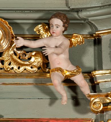 Zdjęcie nr 14: Ołtarz jednoosiowy, jednokondygnacyjny ze zwieńczeniem. Podwójny cokół z wąską, drewnianą mensą ołtarzową, tabernakulum ze spływami wolutowymi. Retabulum flankowane dwiema ćwierć kolumnami skierowanymi po ukosie na zewnątrz, z których każda ujęta parą korynckich, kanelowanych pilastrów dźwigających przełamujące się nad nimi belkowanie i dwa faliste naczółki. Na tle pilastrów, na konsolach stoją dwa uskrzydlone anioły. Zwieńczenie ujęte spływami wolutowymi, zakończone dwiema profilowanym, lekko falistym gzymsem z dwiema stykającymi się wolutami. W polu głównym szeroka, złocona, prostokątna rama z obrazami „Św. Mikołaj” i "Wizja św. Franciszka" na zasuwie, w zwieńczeniu owalny obraz w złoconej ramie z przedstawieniem św. Antoniego. Figury aniołów wydrążone, ukazane w kontrapoście, z dłońmi wysuniętymi do przodu; anioł po lewej trzyma chustę. Ich twarze są owalne o regularnych rysach, z brązowymi puklowanymi włosami sięgającymi ramion. Z tyłu przymocowane duże, złote skrzydła. Ubrane są w długie, złote szaty o ostrym zarysie, odsłaniające klatkę piersiową i jedną z nóg. W partii belkowania para nagich puttów ze złoconymi opaskami na biodrach ujmujących kartusz w rokokowym obramieniu z chrystogramem. Na naczółkach z kolei siedzą nagie putta z przepaskami na biodrach i złotymi skrzydełkami. Na dekorację ornamentalną składają się drobne motywy roślinne, kampanule na ćwierćkolumnach, zwisy róż i gałązek wokół obrazu w zwieńczeniu i efektowna podwójna muszla palmetowa w zwieńczeniu. 
