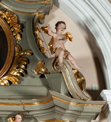 Zdjęcie nr 18: Ołtarz jednoosiowy, jednokondygnacyjny ze zwieńczeniem. Podwójny cokół z wąską, drewnianą mensą ołtarzową, tabernakulum ze spływami wolutowymi. Retabulum flankowane dwiema ćwierć kolumnami skierowanymi po ukosie na zewnątrz, z których każda ujęta parą korynckich, kanelowanych pilastrów dźwigających przełamujące się nad nimi belkowanie i dwa faliste naczółki. Na tle pilastrów, na konsolach stoją dwa uskrzydlone anioły. Zwieńczenie ujęte spływami wolutowymi, zakończone dwiema profilowanym, lekko falistym gzymsem z dwiema stykającymi się wolutami. W polu głównym szeroka, złocona, prostokątna rama z obrazami „Św. Mikołaj” i "Wizja św. Franciszka" na zasuwie, w zwieńczeniu owalny obraz w złoconej ramie z przedstawieniem św. Antoniego. Figury aniołów wydrążone, ukazane w kontrapoście, z dłońmi wysuniętymi do przodu; anioł po lewej trzyma chustę. Ich twarze są owalne o regularnych rysach, z brązowymi puklowanymi włosami sięgającymi ramion. Z tyłu przymocowane duże, złote skrzydła. Ubrane są w długie, złote szaty o ostrym zarysie, odsłaniające klatkę piersiową i jedną z nóg. W partii belkowania para nagich puttów ze złoconymi opaskami na biodrach ujmujących kartusz w rokokowym obramieniu z chrystogramem. Na naczółkach z kolei siedzą nagie putta z przepaskami na biodrach i złotymi skrzydełkami. Na dekorację ornamentalną składają się drobne motywy roślinne, kampanule na ćwierćkolumnach, zwisy róż i gałązek wokół obrazu w zwieńczeniu i efektowna podwójna muszla palmetowa w zwieńczeniu. 
