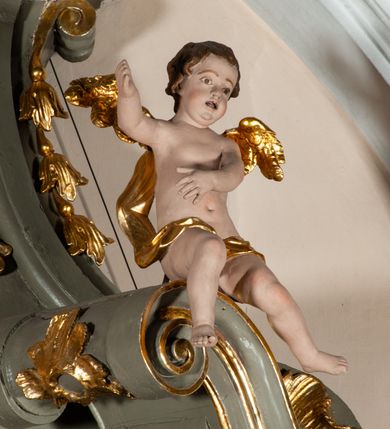 Zdjęcie nr 17: Ołtarz jednoosiowy, jednokondygnacyjny ze zwieńczeniem. Podwójny cokół z wąską, drewnianą mensą ołtarzową, tabernakulum ze spływami wolutowymi. Retabulum flankowane dwiema ćwierć kolumnami skierowanymi po ukosie na zewnątrz, z których każda ujęta parą korynckich, kanelowanych pilastrów dźwigających przełamujące się nad nimi belkowanie i dwa faliste naczółki. Na tle pilastrów, na konsolach stoją dwa uskrzydlone anioły. Zwieńczenie ujęte spływami wolutowymi, zakończone dwiema profilowanym, lekko falistym gzymsem z dwiema stykającymi się wolutami. W polu głównym szeroka, złocona, prostokątna rama z obrazami „Św. Mikołaj” i "Wizja św. Franciszka" na zasuwie, w zwieńczeniu owalny obraz w złoconej ramie z przedstawieniem św. Antoniego. Figury aniołów wydrążone, ukazane w kontrapoście, z dłońmi wysuniętymi do przodu; anioł po lewej trzyma chustę. Ich twarze są owalne o regularnych rysach, z brązowymi puklowanymi włosami sięgającymi ramion. Z tyłu przymocowane duże, złote skrzydła. Ubrane są w długie, złote szaty o ostrym zarysie, odsłaniające klatkę piersiową i jedną z nóg. W partii belkowania para nagich puttów ze złoconymi opaskami na biodrach ujmujących kartusz w rokokowym obramieniu z chrystogramem. Na naczółkach z kolei siedzą nagie putta z przepaskami na biodrach i złotymi skrzydełkami. Na dekorację ornamentalną składają się drobne motywy roślinne, kampanule na ćwierćkolumnach, zwisy róż i gałązek wokół obrazu w zwieńczeniu i efektowna podwójna muszla palmetowa w zwieńczeniu. 
