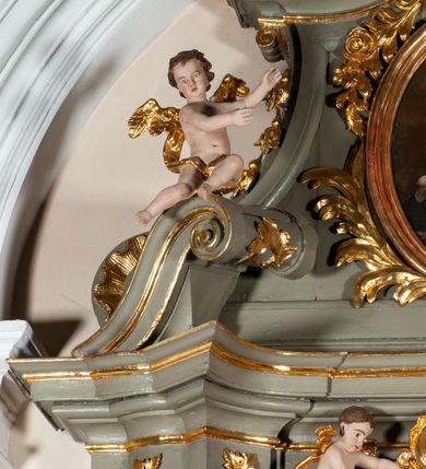 Zdjęcie nr 19: Ołtarz jednoosiowy, jednokondygnacyjny ze zwieńczeniem. Podwójny cokół z wąską, drewnianą mensą ołtarzową, tabernakulum ze spływami wolutowymi. Retabulum flankowane dwiema ćwierć kolumnami skierowanymi po ukosie na zewnątrz, z których każda ujęta parą korynckich, kanelowanych pilastrów dźwigających przełamujące się nad nimi belkowanie i dwa faliste naczółki. Na tle pilastrów, na konsolach stoją dwa uskrzydlone anioły. Zwieńczenie ujęte spływami wolutowymi, zakończone dwiema profilowanym, lekko falistym gzymsem z dwiema stykającymi się wolutami. W polu głównym szeroka, złocona, prostokątna rama z obrazami „Św. Mikołaj” i "Wizja św. Franciszka" na zasuwie, w zwieńczeniu owalny obraz w złoconej ramie z przedstawieniem św. Antoniego. Figury aniołów wydrążone, ukazane w kontrapoście, z dłońmi wysuniętymi do przodu; anioł po lewej trzyma chustę. Ich twarze są owalne o regularnych rysach, z brązowymi puklowanymi włosami sięgającymi ramion. Z tyłu przymocowane duże, złote skrzydła. Ubrane są w długie, złote szaty o ostrym zarysie, odsłaniające klatkę piersiową i jedną z nóg. W partii belkowania para nagich puttów ze złoconymi opaskami na biodrach ujmujących kartusz w rokokowym obramieniu z chrystogramem. Na naczółkach z kolei siedzą nagie putta z przepaskami na biodrach i złotymi skrzydełkami. Na dekorację ornamentalną składają się drobne motywy roślinne, kampanule na ćwierćkolumnach, zwisy róż i gałązek wokół obrazu w zwieńczeniu i efektowna podwójna muszla palmetowa w zwieńczeniu. 
