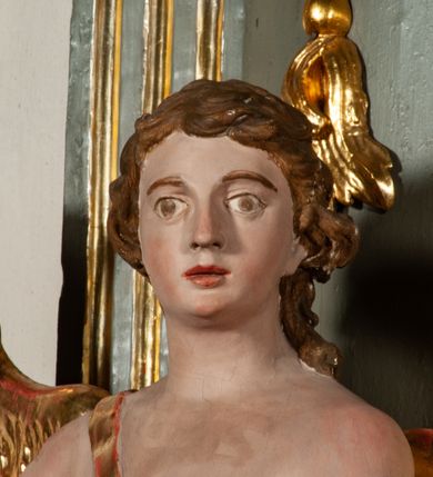 Zdjęcie nr 28: Ołtarz jednoosiowy, jednokondygnacyjny ze zwieńczeniem. Podwójny cokół z wąską, drewnianą mensą ołtarzową, tabernakulum ze spływami wolutowymi. Retabulum flankowane dwiema ćwierć kolumnami skierowanymi po ukosie na zewnątrz, z których każda ujęta parą korynckich, kanelowanych pilastrów dźwigających przełamujące się nad nimi belkowanie i dwa faliste naczółki. Na tle pilastrów, na konsolach stoją dwa uskrzydlone anioły. Zwieńczenie ujęte spływami wolutowymi, zakończone dwiema profilowanym, lekko falistym gzymsem z dwiema stykającymi się wolutami. W polu głównym szeroka, złocona, prostokątna rama z obrazami „Św. Mikołaj” i "Wizja św. Franciszka" na zasuwie, w zwieńczeniu owalny obraz w złoconej ramie z przedstawieniem św. Antoniego. Figury aniołów wydrążone, ukazane w kontrapoście, z dłońmi wysuniętymi do przodu; anioł po lewej trzyma chustę. Ich twarze są owalne o regularnych rysach, z brązowymi puklowanymi włosami sięgającymi ramion. Z tyłu przymocowane duże, złote skrzydła. Ubrane są w długie, złote szaty o ostrym zarysie, odsłaniające klatkę piersiową i jedną z nóg. W partii belkowania para nagich puttów ze złoconymi opaskami na biodrach ujmujących kartusz w rokokowym obramieniu z chrystogramem. Na naczółkach z kolei siedzą nagie putta z przepaskami na biodrach i złotymi skrzydełkami. Na dekorację ornamentalną składają się drobne motywy roślinne, kampanule na ćwierćkolumnach, zwisy róż i gałązek wokół obrazu w zwieńczeniu i efektowna podwójna muszla palmetowa w zwieńczeniu. 
