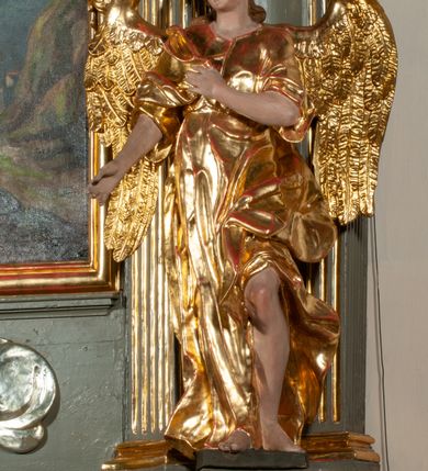 Zdjęcie nr 11: Ołtarz jednoosiowy, jednokondygnacyjny ze zwieńczeniem. Podwójny cokół z wąską, drewnianą mensą ołtarzową, tabernakulum ze spływami wolutowymi. Retabulum flankowane dwiema ćwierć kolumnami skierowanymi po ukosie na zewnątrz, z których każda ujęta parą korynckich, kanelowanych pilastrów dźwigających przełamujące się nad nimi belkowanie i dwa faliste naczółki. Na tle pilastrów, na konsolach stoją dwa uskrzydlone anioły. Zwieńczenie ujęte spływami wolutowymi, zakończone dwiema profilowanym, lekko falistym gzymsem z dwiema stykającymi się wolutami. W polu głównym szeroka, złocona, prostokątna rama z obrazami „Św. Mikołaj” i "Wizja św. Franciszka" na zasuwie, w zwieńczeniu owalny obraz w złoconej ramie z przedstawieniem św. Antoniego. Figury aniołów wydrążone, ukazane w kontrapoście, z dłońmi wysuniętymi do przodu; anioł po lewej trzyma chustę. Ich twarze są owalne o regularnych rysach, z brązowymi puklowanymi włosami sięgającymi ramion. Z tyłu przymocowane duże, złote skrzydła. Ubrane są w długie, złote szaty o ostrym zarysie, odsłaniające klatkę piersiową i jedną z nóg. W partii belkowania para nagich puttów ze złoconymi opaskami na biodrach ujmujących kartusz w rokokowym obramieniu z chrystogramem. Na naczółkach z kolei siedzą nagie putta z przepaskami na biodrach i złotymi skrzydełkami. Na dekorację ornamentalną składają się drobne motywy roślinne, kampanule na ćwierćkolumnach, zwisy róż i gałązek wokół obrazu w zwieńczeniu i efektowna podwójna muszla palmetowa w zwieńczeniu. 
