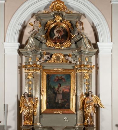 Zdjęcie nr 1: Ołtarz  jednoosiowy, jednokondygnacyjny ze zwieńczeniem. Podwójny cokół z wąską, drewnianą mensą ołtarzową, tabernakulum ze spływami wolutowymi. Retabulum flankowane dwiema ćwierć kolumnami skierowanymi po ukosie na zewnątrz, z których każda ujęta parą korynckich, kanelowanych pilastrów dźwigających przełamujące się nad nimi belkowanie i dwa faliste naczółki. Na tle pilastrów, na konsolach stoją dwa uskrzydlone anioły. Zwieńczenie ujęte spływami wolutowymi, zakończone profilowanym, lekko falistym gzymsem z dwiema stykającymi się wolutami. W polu głównym szeroka, złocona, prostokątna rama z obrazem &quot;Św. Szymon Oracz&quot;, w zwieńczeniu owalny obraz w złoconej ramie z przedstawieniem św. Michała Archanioła. Figury aniołów wydrążone, ukazane w kontrapoście, o prawidłowych proporcjach ciała, w lekkim przechyleniu na bok, z dłońmi ułożonymi do gry na instrumencie szarpanym. Ich twarze są owalne o regularnych rysach, z brązowymi puklowanymi włosami sięgającymi ramion. Z tyłu przymocowane duże, złote skrzydła. Ubrani są w długie, złote szaty o ostrym zarysie. W partii belkowania para nagich puttów ze złoconymi opaskami na biodrach ujmują kartusz w rokokowym obramieniu. Na naczółkach z kolei siedzą nagie putta z przepaskami na biodrach i złotymi skrzydełkami. Na dekorację ornamentalną składają się drobne motywy roślinne, kampanule na ćwierćkolumnach, zwisy róż i gałązek wokół obrazu w zwieńczeniu i efektowna podwójna muszla palmetowa w zwieńczeniu. 



