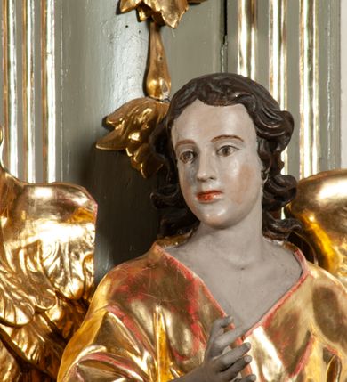 Zdjęcie nr 30: Ołtarz  jednoosiowy, jednokondygnacyjny ze zwieńczeniem. Podwójny cokół z wąską, drewnianą mensą ołtarzową, tabernakulum ze spływami wolutowymi. Retabulum flankowane dwiema ćwierć kolumnami skierowanymi po ukosie na zewnątrz, z których każda ujęta parą korynckich, kanelowanych pilastrów dźwigających przełamujące się nad nimi belkowanie i dwa faliste naczółki. Na tle pilastrów, na konsolach stoją dwa uskrzydlone anioły. Zwieńczenie ujęte spływami wolutowymi, zakończone profilowanym, lekko falistym gzymsem z dwiema stykającymi się wolutami. W polu głównym szeroka, złocona, prostokątna rama z obrazem "Św. Szymon Oracz", w zwieńczeniu owalny obraz w złoconej ramie z przedstawieniem św. Michała Archanioła. Figury aniołów wydrążone, ukazane w kontrapoście, o prawidłowych proporcjach ciała, w lekkim przechyleniu na bok, z dłońmi ułożonymi do gry na instrumencie szarpanym. Ich twarze są owalne o regularnych rysach, z brązowymi puklowanymi włosami sięgającymi ramion. Z tyłu przymocowane duże, złote skrzydła. Ubrani są w długie, złote szaty o ostrym zarysie. W partii belkowania para nagich puttów ze złoconymi opaskami na biodrach ujmują kartusz w rokokowym obramieniu. Na naczółkach z kolei siedzą nagie putta z przepaskami na biodrach i złotymi skrzydełkami. Na dekorację ornamentalną składają się drobne motywy roślinne, kampanule na ćwierćkolumnach, zwisy róż i gałązek wokół obrazu w zwieńczeniu i efektowna podwójna muszla palmetowa w zwieńczeniu. 



