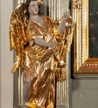 Zdjęcie nr 4: Ołtarz  jednoosiowy, jednokondygnacyjny ze zwieńczeniem. Podwójny cokół z wąską, drewnianą mensą ołtarzową, tabernakulum ze spływami wolutowymi. Retabulum flankowane dwiema ćwierć kolumnami skierowanymi po ukosie na zewnątrz, z których każda ujęta parą korynckich, kanelowanych pilastrów dźwigających przełamujące się nad nimi belkowanie i dwa faliste naczółki. Na tle pilastrów, na konsolach stoją dwa uskrzydlone anioły. Zwieńczenie ujęte spływami wolutowymi, zakończone profilowanym, lekko falistym gzymsem z dwiema stykającymi się wolutami. W polu głównym szeroka, złocona, prostokątna rama z obrazem "Św. Szymon Oracz", w zwieńczeniu owalny obraz w złoconej ramie z przedstawieniem św. Michała Archanioła. Figury aniołów wydrążone, ukazane w kontrapoście, o prawidłowych proporcjach ciała, w lekkim przechyleniu na bok, z dłońmi ułożonymi do gry na instrumencie szarpanym. Ich twarze są owalne o regularnych rysach, z brązowymi puklowanymi włosami sięgającymi ramion. Z tyłu przymocowane duże, złote skrzydła. Ubrani są w długie, złote szaty o ostrym zarysie. W partii belkowania para nagich puttów ze złoconymi opaskami na biodrach ujmują kartusz w rokokowym obramieniu. Na naczółkach z kolei siedzą nagie putta z przepaskami na biodrach i złotymi skrzydełkami. Na dekorację ornamentalną składają się drobne motywy roślinne, kampanule na ćwierćkolumnach, zwisy róż i gałązek wokół obrazu w zwieńczeniu i efektowna podwójna muszla palmetowa w zwieńczeniu. 



