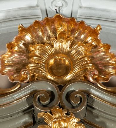 Zdjęcie nr 9: Ołtarz  jednoosiowy, jednokondygnacyjny ze zwieńczeniem. Podwójny cokół z wąską, drewnianą mensą ołtarzową, tabernakulum ze spływami wolutowymi. Retabulum flankowane dwiema ćwierć kolumnami skierowanymi po ukosie na zewnątrz, z których każda ujęta parą korynckich, kanelowanych pilastrów dźwigających przełamujące się nad nimi belkowanie i dwa faliste naczółki. Na tle pilastrów, na konsolach stoją dwa uskrzydlone anioły. Zwieńczenie ujęte spływami wolutowymi, zakończone profilowanym, lekko falistym gzymsem z dwiema stykającymi się wolutami. W polu głównym szeroka, złocona, prostokątna rama z obrazem "Św. Szymon Oracz", w zwieńczeniu owalny obraz w złoconej ramie z przedstawieniem św. Michała Archanioła. Figury aniołów wydrążone, ukazane w kontrapoście, o prawidłowych proporcjach ciała, w lekkim przechyleniu na bok, z dłońmi ułożonymi do gry na instrumencie szarpanym. Ich twarze są owalne o regularnych rysach, z brązowymi puklowanymi włosami sięgającymi ramion. Z tyłu przymocowane duże, złote skrzydła. Ubrani są w długie, złote szaty o ostrym zarysie. W partii belkowania para nagich puttów ze złoconymi opaskami na biodrach ujmują kartusz w rokokowym obramieniu. Na naczółkach z kolei siedzą nagie putta z przepaskami na biodrach i złotymi skrzydełkami. Na dekorację ornamentalną składają się drobne motywy roślinne, kampanule na ćwierćkolumnach, zwisy róż i gałązek wokół obrazu w zwieńczeniu i efektowna podwójna muszla palmetowa w zwieńczeniu. 



