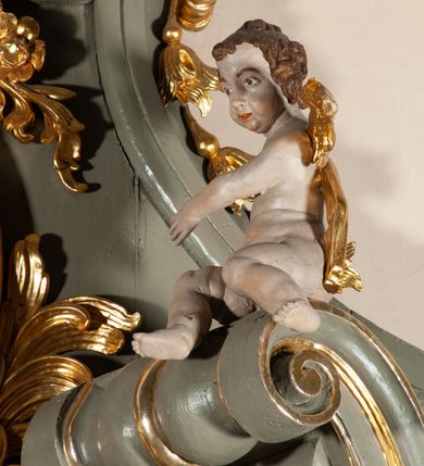 Zdjęcie nr 16: Ołtarz  jednoosiowy, jednokondygnacyjny ze zwieńczeniem. Podwójny cokół z wąską, drewnianą mensą ołtarzową, tabernakulum ze spływami wolutowymi. Retabulum flankowane dwiema ćwierć kolumnami skierowanymi po ukosie na zewnątrz, z których każda ujęta parą korynckich, kanelowanych pilastrów dźwigających przełamujące się nad nimi belkowanie i dwa faliste naczółki. Na tle pilastrów, na konsolach stoją dwa uskrzydlone anioły. Zwieńczenie ujęte spływami wolutowymi, zakończone profilowanym, lekko falistym gzymsem z dwiema stykającymi się wolutami. W polu głównym szeroka, złocona, prostokątna rama z obrazem "Św. Szymon Oracz", w zwieńczeniu owalny obraz w złoconej ramie z przedstawieniem św. Michała Archanioła. Figury aniołów wydrążone, ukazane w kontrapoście, o prawidłowych proporcjach ciała, w lekkim przechyleniu na bok, z dłońmi ułożonymi do gry na instrumencie szarpanym. Ich twarze są owalne o regularnych rysach, z brązowymi puklowanymi włosami sięgającymi ramion. Z tyłu przymocowane duże, złote skrzydła. Ubrani są w długie, złote szaty o ostrym zarysie. W partii belkowania para nagich puttów ze złoconymi opaskami na biodrach ujmują kartusz w rokokowym obramieniu. Na naczółkach z kolei siedzą nagie putta z przepaskami na biodrach i złotymi skrzydełkami. Na dekorację ornamentalną składają się drobne motywy roślinne, kampanule na ćwierćkolumnach, zwisy róż i gałązek wokół obrazu w zwieńczeniu i efektowna podwójna muszla palmetowa w zwieńczeniu. 



