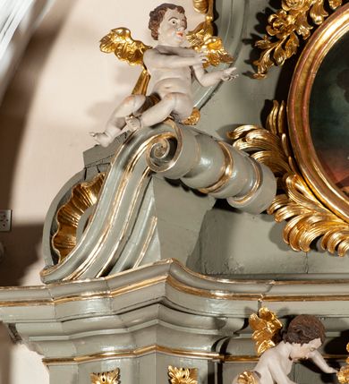 Zdjęcie nr 19: Ołtarz  jednoosiowy, jednokondygnacyjny ze zwieńczeniem. Podwójny cokół z wąską, drewnianą mensą ołtarzową, tabernakulum ze spływami wolutowymi. Retabulum flankowane dwiema ćwierć kolumnami skierowanymi po ukosie na zewnątrz, z których każda ujęta parą korynckich, kanelowanych pilastrów dźwigających przełamujące się nad nimi belkowanie i dwa faliste naczółki. Na tle pilastrów, na konsolach stoją dwa uskrzydlone anioły. Zwieńczenie ujęte spływami wolutowymi, zakończone profilowanym, lekko falistym gzymsem z dwiema stykającymi się wolutami. W polu głównym szeroka, złocona, prostokątna rama z obrazem "Św. Szymon Oracz", w zwieńczeniu owalny obraz w złoconej ramie z przedstawieniem św. Michała Archanioła. Figury aniołów wydrążone, ukazane w kontrapoście, o prawidłowych proporcjach ciała, w lekkim przechyleniu na bok, z dłońmi ułożonymi do gry na instrumencie szarpanym. Ich twarze są owalne o regularnych rysach, z brązowymi puklowanymi włosami sięgającymi ramion. Z tyłu przymocowane duże, złote skrzydła. Ubrani są w długie, złote szaty o ostrym zarysie. W partii belkowania para nagich puttów ze złoconymi opaskami na biodrach ujmują kartusz w rokokowym obramieniu. Na naczółkach z kolei siedzą nagie putta z przepaskami na biodrach i złotymi skrzydełkami. Na dekorację ornamentalną składają się drobne motywy roślinne, kampanule na ćwierćkolumnach, zwisy róż i gałązek wokół obrazu w zwieńczeniu i efektowna podwójna muszla palmetowa w zwieńczeniu. 




