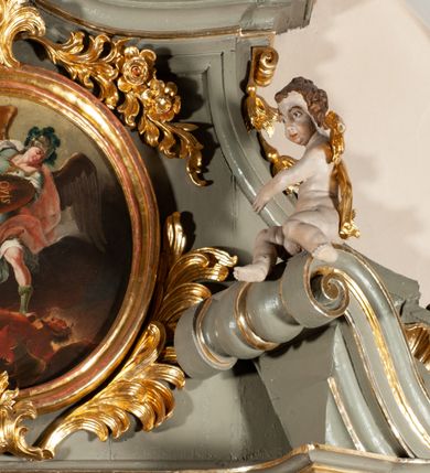 Zdjęcie nr 17: Ołtarz  jednoosiowy, jednokondygnacyjny ze zwieńczeniem. Podwójny cokół z wąską, drewnianą mensą ołtarzową, tabernakulum ze spływami wolutowymi. Retabulum flankowane dwiema ćwierć kolumnami skierowanymi po ukosie na zewnątrz, z których każda ujęta parą korynckich, kanelowanych pilastrów dźwigających przełamujące się nad nimi belkowanie i dwa faliste naczółki. Na tle pilastrów, na konsolach stoją dwa uskrzydlone anioły. Zwieńczenie ujęte spływami wolutowymi, zakończone profilowanym, lekko falistym gzymsem z dwiema stykającymi się wolutami. W polu głównym szeroka, złocona, prostokątna rama z obrazem "Św. Szymon Oracz", w zwieńczeniu owalny obraz w złoconej ramie z przedstawieniem św. Michała Archanioła. Figury aniołów wydrążone, ukazane w kontrapoście, o prawidłowych proporcjach ciała, w lekkim przechyleniu na bok, z dłońmi ułożonymi do gry na instrumencie szarpanym. Ich twarze są owalne o regularnych rysach, z brązowymi puklowanymi włosami sięgającymi ramion. Z tyłu przymocowane duże, złote skrzydła. Ubrani są w długie, złote szaty o ostrym zarysie. W partii belkowania para nagich puttów ze złoconymi opaskami na biodrach ujmują kartusz w rokokowym obramieniu. Na naczółkach z kolei siedzą nagie putta z przepaskami na biodrach i złotymi skrzydełkami. Na dekorację ornamentalną składają się drobne motywy roślinne, kampanule na ćwierćkolumnach, zwisy róż i gałązek wokół obrazu w zwieńczeniu i efektowna podwójna muszla palmetowa w zwieńczeniu. 



