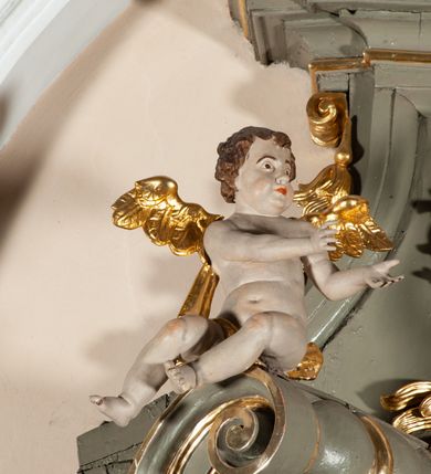 Zdjęcie nr 15: Ołtarz  jednoosiowy, jednokondygnacyjny ze zwieńczeniem. Podwójny cokół z wąską, drewnianą mensą ołtarzową, tabernakulum ze spływami wolutowymi. Retabulum flankowane dwiema ćwierć kolumnami skierowanymi po ukosie na zewnątrz, z których każda ujęta parą korynckich, kanelowanych pilastrów dźwigających przełamujące się nad nimi belkowanie i dwa faliste naczółki. Na tle pilastrów, na konsolach stoją dwa uskrzydlone anioły. Zwieńczenie ujęte spływami wolutowymi, zakończone profilowanym, lekko falistym gzymsem z dwiema stykającymi się wolutami. W polu głównym szeroka, złocona, prostokątna rama z obrazem "Św. Szymon Oracz", w zwieńczeniu owalny obraz w złoconej ramie z przedstawieniem św. Michała Archanioła. Figury aniołów wydrążone, ukazane w kontrapoście, o prawidłowych proporcjach ciała, w lekkim przechyleniu na bok, z dłońmi ułożonymi do gry na instrumencie szarpanym. Ich twarze są owalne o regularnych rysach, z brązowymi puklowanymi włosami sięgającymi ramion. Z tyłu przymocowane duże, złote skrzydła. Ubrani są w długie, złote szaty o ostrym zarysie. W partii belkowania para nagich puttów ze złoconymi opaskami na biodrach ujmują kartusz w rokokowym obramieniu. Na naczółkach z kolei siedzą nagie putta z przepaskami na biodrach i złotymi skrzydełkami. Na dekorację ornamentalną składają się drobne motywy roślinne, kampanule na ćwierćkolumnach, zwisy róż i gałązek wokół obrazu w zwieńczeniu i efektowna podwójna muszla palmetowa w zwieńczeniu. 



