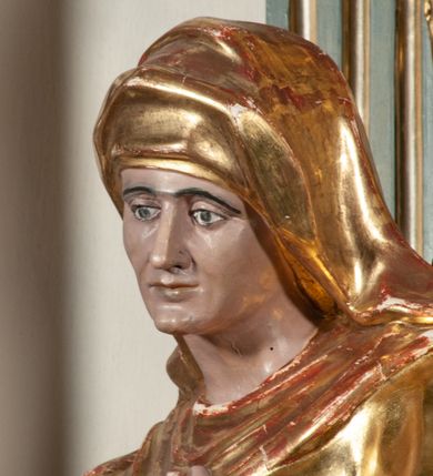 Zdjęcie nr 9: Ołtarz jednoosiowy, jednokondygnacyjny ze zwieńczeniem. Podwójny cokół z wąską, drewnianą mensą ołtarzową, wybrzuszoną. Na niej stoi tabernakulum ujęte narożnie ustawionymi spływami wolutowymi, zwieńczone spłaszczoną kopułką ze spływami wolutowymi. Retabulum flankowane dwiema ćwierć kolumnami skierowanymi po ukosie na zewnątrz, z których każda ujęta parą korynckich, kanelowanych pilastrów dźwigających przełamujące się nad nimi belkowanie i dwa faliste naczółki. Na tle pilastrów, na konsolach stoją figury św. Anny i św. Joachima oraz unoszą się na chmurach flankujące obraz uskrzydlone anioły. Zwieńczenie ujęte spływami wolutowymi, zakończone profilowanym, lekko falistym gzymsem z dwiema stykającymi się wolutami. N naczółkach dwa uskrzydlone, przepasane opaską na biodrach aniołki. W polu głównym szeroka, złocona, prostokątna rama z obrazem Matki Boskiej z Dzieciątkiem i koroną w partii belkowania, a w zwieńczeniu owalny obraz w złoconej ramie z przedstawieniem św. Józefa z Dzieciątkiem. Figury św. Anny i św. Joachima ukazane w lekkim kontrapoście, w długich, obficie fałdowanych szatach. Anna trzyma prawą rękę na piersi, w lewej przytrzymuje połę płaszcza, natomiast Joachim ręce składa w geście modlitwy. Anioły klęczą na chmurach, usytuowanych na różnych poziomach, ubrane są w miękko, ale drobno fałdowane szaty, odsłaniające ich ramiona i górną część klatki piersiowej i wskazujący na obraz. Na dekorację ornamentalną składają się drobne motywy roślinne, kampanule na ćwierćkolumnach, zwisy róż i gałązek palm wokół obrazu w zwieńczeniu i efektowna podwójna muszla palmetowa w zwieńczeniu. 