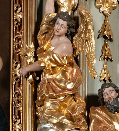 Zdjęcie nr 11: Ołtarz jednoosiowy, jednokondygnacyjny ze zwieńczeniem. Podwójny cokół z wąską, drewnianą mensą ołtarzową, wybrzuszoną. Na niej stoi tabernakulum ujęte narożnie ustawionymi spływami wolutowymi, zwieńczone spłaszczoną kopułką ze spływami wolutowymi. Retabulum flankowane dwiema ćwierć kolumnami skierowanymi po ukosie na zewnątrz, z których każda ujęta parą korynckich, kanelowanych pilastrów dźwigających przełamujące się nad nimi belkowanie i dwa faliste naczółki. Na tle pilastrów, na konsolach stoją figury św. Anny i św. Joachima oraz unoszą się na chmurach flankujące obraz uskrzydlone anioły. Zwieńczenie ujęte spływami wolutowymi, zakończone profilowanym, lekko falistym gzymsem z dwiema stykającymi się wolutami. N naczółkach dwa uskrzydlone, przepasane opaską na biodrach aniołki. W polu głównym szeroka, złocona, prostokątna rama z obrazem Matki Boskiej z Dzieciątkiem i koroną w partii belkowania, a w zwieńczeniu owalny obraz w złoconej ramie z przedstawieniem św. Józefa z Dzieciątkiem. Figury św. Anny i św. Joachima ukazane w lekkim kontrapoście, w długich, obficie fałdowanych szatach. Anna trzyma prawą rękę na piersi, w lewej przytrzymuje połę płaszcza, natomiast Joachim ręce składa w geście modlitwy. Anioły klęczą na chmurach, usytuowanych na różnych poziomach, ubrane są w miękko, ale drobno fałdowane szaty, odsłaniające ich ramiona i górną część klatki piersiowej i wskazujący na obraz. Na dekorację ornamentalną składają się drobne motywy roślinne, kampanule na ćwierćkolumnach, zwisy róż i gałązek palm wokół obrazu w zwieńczeniu i efektowna podwójna muszla palmetowa w zwieńczeniu. 