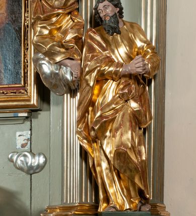 Zdjęcie nr 16: Ołtarz jednoosiowy, jednokondygnacyjny ze zwieńczeniem. Podwójny cokół z wąską, drewnianą mensą ołtarzową, wybrzuszoną. Na niej stoi tabernakulum ujęte narożnie ustawionymi spływami wolutowymi, zwieńczone spłaszczoną kopułką ze spływami wolutowymi. Retabulum flankowane dwiema ćwierć kolumnami skierowanymi po ukosie na zewnątrz, z których każda ujęta parą korynckich, kanelowanych pilastrów dźwigających przełamujące się nad nimi belkowanie i dwa faliste naczółki. Na tle pilastrów, na konsolach stoją figury św. Anny i św. Joachima oraz unoszą się na chmurach flankujące obraz uskrzydlone anioły. Zwieńczenie ujęte spływami wolutowymi, zakończone profilowanym, lekko falistym gzymsem z dwiema stykającymi się wolutami. N naczółkach dwa uskrzydlone, przepasane opaską na biodrach aniołki. W polu głównym szeroka, złocona, prostokątna rama z obrazem Matki Boskiej z Dzieciątkiem i koroną w partii belkowania, a w zwieńczeniu owalny obraz w złoconej ramie z przedstawieniem św. Józefa z Dzieciątkiem. Figury św. Anny i św. Joachima ukazane w lekkim kontrapoście, w długich, obficie fałdowanych szatach. Anna trzyma prawą rękę na piersi, w lewej przytrzymuje połę płaszcza, natomiast Joachim ręce składa w geście modlitwy. Anioły klęczą na chmurach, usytuowanych na różnych poziomach, ubrane są w miękko, ale drobno fałdowane szaty, odsłaniające ich ramiona i górną część klatki piersiowej i wskazujący na obraz. Na dekorację ornamentalną składają się drobne motywy roślinne, kampanule na ćwierćkolumnach, zwisy róż i gałązek palm wokół obrazu w zwieńczeniu i efektowna podwójna muszla palmetowa w zwieńczeniu. 