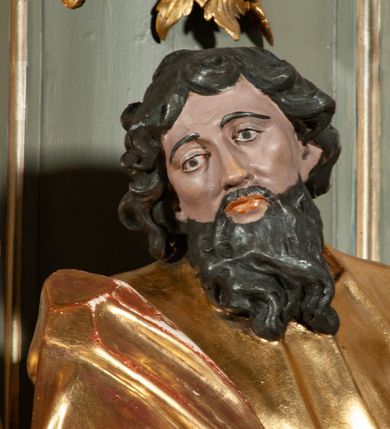 Zdjęcie nr 17: Ołtarz jednoosiowy, jednokondygnacyjny ze zwieńczeniem. Podwójny cokół z wąską, drewnianą mensą ołtarzową, wybrzuszoną. Na niej stoi tabernakulum ujęte narożnie ustawionymi spływami wolutowymi, zwieńczone spłaszczoną kopułką ze spływami wolutowymi. Retabulum flankowane dwiema ćwierć kolumnami skierowanymi po ukosie na zewnątrz, z których każda ujęta parą korynckich, kanelowanych pilastrów dźwigających przełamujące się nad nimi belkowanie i dwa faliste naczółki. Na tle pilastrów, na konsolach stoją figury św. Anny i św. Joachima oraz unoszą się na chmurach flankujące obraz uskrzydlone anioły. Zwieńczenie ujęte spływami wolutowymi, zakończone profilowanym, lekko falistym gzymsem z dwiema stykającymi się wolutami. N naczółkach dwa uskrzydlone, przepasane opaską na biodrach aniołki. W polu głównym szeroka, złocona, prostokątna rama z obrazem Matki Boskiej z Dzieciątkiem i koroną w partii belkowania, a w zwieńczeniu owalny obraz w złoconej ramie z przedstawieniem św. Józefa z Dzieciątkiem. Figury św. Anny i św. Joachima ukazane w lekkim kontrapoście, w długich, obficie fałdowanych szatach. Anna trzyma prawą rękę na piersi, w lewej przytrzymuje połę płaszcza, natomiast Joachim ręce składa w geście modlitwy. Anioły klęczą na chmurach, usytuowanych na różnych poziomach, ubrane są w miękko, ale drobno fałdowane szaty, odsłaniające ich ramiona i górną część klatki piersiowej i wskazujący na obraz. Na dekorację ornamentalną składają się drobne motywy roślinne, kampanule na ćwierćkolumnach, zwisy róż i gałązek palm wokół obrazu w zwieńczeniu i efektowna podwójna muszla palmetowa w zwieńczeniu. 