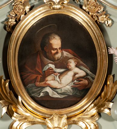 Zdjęcie nr 23: Ołtarz jednoosiowy, jednokondygnacyjny ze zwieńczeniem. Podwójny cokół z wąską, drewnianą mensą ołtarzową, wybrzuszoną. Na niej stoi tabernakulum ujęte narożnie ustawionymi spływami wolutowymi, zwieńczone spłaszczoną kopułką ze spływami wolutowymi. Retabulum flankowane dwiema ćwierć kolumnami skierowanymi po ukosie na zewnątrz, z których każda ujęta parą korynckich, kanelowanych pilastrów dźwigających przełamujące się nad nimi belkowanie i dwa faliste naczółki. Na tle pilastrów, na konsolach stoją figury św. Anny i św. Joachima oraz unoszą się na chmurach flankujące obraz uskrzydlone anioły. Zwieńczenie ujęte spływami wolutowymi, zakończone profilowanym, lekko falistym gzymsem z dwiema stykającymi się wolutami. N naczółkach dwa uskrzydlone, przepasane opaską na biodrach aniołki. W polu głównym szeroka, złocona, prostokątna rama z obrazem Matki Boskiej z Dzieciątkiem i koroną w partii belkowania, a w zwieńczeniu owalny obraz w złoconej ramie z przedstawieniem św. Józefa z Dzieciątkiem. Figury św. Anny i św. Joachima ukazane w lekkim kontrapoście, w długich, obficie fałdowanych szatach. Anna trzyma prawą rękę na piersi, w lewej przytrzymuje połę płaszcza, natomiast Joachim ręce składa w geście modlitwy. Anioły klęczą na chmurach, usytuowanych na różnych poziomach, ubrane są w miękko, ale drobno fałdowane szaty, odsłaniające ich ramiona i górną część klatki piersiowej i wskazujący na obraz. Na dekorację ornamentalną składają się drobne motywy roślinne, kampanule na ćwierćkolumnach, zwisy róż i gałązek palm wokół obrazu w zwieńczeniu i efektowna podwójna muszla palmetowa w zwieńczeniu. 