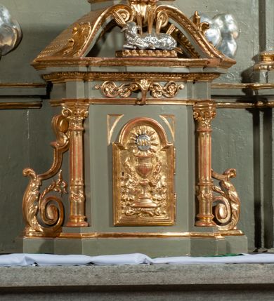 Zdjęcie nr 9: Ołtarz jednoosiowy, jednokondygnacyjny ze zwieńczeniem. Podwójny cokół z wąską, drewnianą mensą ołtarzową, wybrzuszoną. Na niej stoi tabernakulum ujęte kolumienkami i spływami wolutowymi, zwieńczone dwoma zwróconymi do siebie naczółkami z niewielką figurą baranka na tle promieni. Retabulum flankowane dwiema ćwierć kolumnami skierowanymi po ukosie na zewnątrz, z których każda ujęta parą korynckich, kanelowanych pilastrów dźwigających przełamujące się nad nimi belkowanie i dwa faliste naczółki. Na tle pilastrów, na konsolach stoją dwie figury egzotycznych mężczyzn. Zwieńczenie ujęte spływami wolutowymi, zakończone profilowanym, lekko falistym gzymsem z dwiema stykającymi się wolutami. W polu głównym szeroka, złocona, prostokątna rama z obrazem "Męczeństwo św. Bartłomieja", w zwieńczeniu owalny obraz w złoconej ramie z przedstawieniem Anioła Stróża. 
Figury egzotycznych (o typach wschodnich) mężczyzn ukazane w kontrapoście, o prawidłowych proporcjach ciała, z rękami uniesionymi przed siebie, na wysokości klatki piersiowej. Ich twarze są pełne, okrągłe o szerokich nosach i wydatnych, lekko otwartych ustach, na głowie krótkie, kręcone, ciemne włosy przytrzymane na czole złoconymi opaskami. Biodra okalają sięgające kolan spódniczki ze srebrnych piór. Mężczyzna po lewej stronie trzyma skórę z twarzą św. Bartłomieja osłaniającą część jego ciała, a postać po prawej nosi na plechach płaszcz sięgający stóp. Na dekorację ornamentalną składają się drobne motywy roślinne, kampanule na ćwierćkolumnach, kartusz ujęty drobnymi rocaille’ami, zwisy róż i gałązek palm wokół obrazu w zwieńczeniu i efektowna podwójna muszla palmetowa w zwieńczeniu. 
