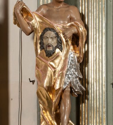 Zdjęcie nr 23: Ołtarz jednoosiowy, jednokondygnacyjny ze zwieńczeniem. Podwójny cokół z wąską, drewnianą mensą ołtarzową, wybrzuszoną. Na niej stoi tabernakulum ujęte kolumienkami i spływami wolutowymi, zwieńczone dwoma zwróconymi do siebie naczółkami z niewielką figurą baranka na tle promieni. Retabulum flankowane dwiema ćwierć kolumnami skierowanymi po ukosie na zewnątrz, z których każda ujęta parą korynckich, kanelowanych pilastrów dźwigających przełamujące się nad nimi belkowanie i dwa faliste naczółki. Na tle pilastrów, na konsolach stoją dwie figury egzotycznych mężczyzn. Zwieńczenie ujęte spływami wolutowymi, zakończone profilowanym, lekko falistym gzymsem z dwiema stykającymi się wolutami. W polu głównym szeroka, złocona, prostokątna rama z obrazem "Męczeństwo św. Bartłomieja", w zwieńczeniu owalny obraz w złoconej ramie z przedstawieniem Anioła Stróża. 
Figury egzotycznych (o typach wschodnich) mężczyzn ukazane w kontrapoście, o prawidłowych proporcjach ciała, z rękami uniesionymi przed siebie, na wysokości klatki piersiowej. Ich twarze są pełne, okrągłe o szerokich nosach i wydatnych, lekko otwartych ustach, na głowie krótkie, kręcone, ciemne włosy przytrzymane na czole złoconymi opaskami. Biodra okalają sięgające kolan spódniczki ze srebrnych piór. Mężczyzna po lewej stronie trzyma skórę z twarzą św. Bartłomieja osłaniającą część jego ciała, a postać po prawej nosi na plechach płaszcz sięgający stóp. Na dekorację ornamentalną składają się drobne motywy roślinne, kampanule na ćwierćkolumnach, kartusz ujęty drobnymi rocaille’ami, zwisy róż i gałązek palm wokół obrazu w zwieńczeniu i efektowna podwójna muszla palmetowa w zwieńczeniu. 
