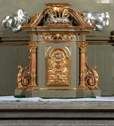 Zdjęcie nr 10: Ołtarz jednoosiowy, jednokondygnacyjny ze zwieńczeniem. Podwójny cokół z wąską, drewnianą mensą ołtarzową, wybrzuszoną. Na niej stoi tabernakulum ujęte kolumienkami i spływami wolutowymi, zwieńczone dwoma zwróconymi do siebie naczółkami z niewielką figurą baranka na tle promieni. Retabulum flankowane dwiema ćwierć kolumnami skierowanymi po ukosie na zewnątrz, z których każda ujęta parą korynckich, kanelowanych pilastrów dźwigających przełamujące się nad nimi belkowanie i dwa faliste naczółki. Na tle pilastrów, na konsolach stoją dwie figury egzotycznych mężczyzn. Zwieńczenie ujęte spływami wolutowymi, zakończone profilowanym, lekko falistym gzymsem z dwiema stykającymi się wolutami. W polu głównym szeroka, złocona, prostokątna rama z obrazem &quot;Męczeństwo św. Bartłomieja&quot;, w zwieńczeniu owalny obraz w złoconej ramie z przedstawieniem Anioła Stróża. 
Figury egzotycznych (o typach wschodnich) mężczyzn ukazane w kontrapoście, o prawidłowych proporcjach ciała, z rękami uniesionymi przed siebie, na wysokości klatki piersiowej. Ich twarze są pełne, okrągłe o szerokich nosach i wydatnych, lekko otwartych ustach, na głowie krótkie, kręcone, ciemne włosy przytrzymane na czole złoconymi opaskami. Biodra okalają sięgające kolan spódniczki ze srebrnych piór. Mężczyzna po lewej stronie trzyma skórę z twarzą św. Bartłomieja osłaniającą część jego ciała, a postać po prawej nosi na plechach płaszcz sięgający stóp. Na dekorację ornamentalną składają się drobne motywy roślinne, kampanule na ćwierćkolumnach, kartusz ujęty drobnymi rocaille’ami, zwisy róż i gałązek palm wokół obrazu w zwieńczeniu i efektowna podwójna muszla palmetowa w zwieńczeniu. 
