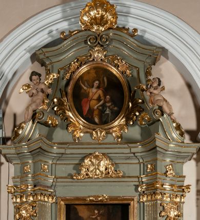 Zdjęcie nr 2: Ołtarz jednoosiowy, jednokondygnacyjny ze zwieńczeniem. Podwójny cokół z wąską, drewnianą mensą ołtarzową, wybrzuszoną. Na niej stoi tabernakulum ujęte kolumienkami i spływami wolutowymi, zwieńczone dwoma zwróconymi do siebie naczółkami z niewielką figurą baranka na tle promieni. Retabulum flankowane dwiema ćwierć kolumnami skierowanymi po ukosie na zewnątrz, z których każda ujęta parą korynckich, kanelowanych pilastrów dźwigających przełamujące się nad nimi belkowanie i dwa faliste naczółki. Na tle pilastrów, na konsolach stoją dwie figury egzotycznych mężczyzn. Zwieńczenie ujęte spływami wolutowymi, zakończone profilowanym, lekko falistym gzymsem z dwiema stykającymi się wolutami. W polu głównym szeroka, złocona, prostokątna rama z obrazem "Męczeństwo św. Bartłomieja", w zwieńczeniu owalny obraz w złoconej ramie z przedstawieniem Anioła Stróża. 
Figury egzotycznych (o typach wschodnich) mężczyzn ukazane w kontrapoście, o prawidłowych proporcjach ciała, z rękami uniesionymi przed siebie, na wysokości klatki piersiowej. Ich twarze są pełne, okrągłe o szerokich nosach i wydatnych, lekko otwartych ustach, na głowie krótkie, kręcone, ciemne włosy przytrzymane na czole złoconymi opaskami. Biodra okalają sięgające kolan spódniczki ze srebrnych piór. Mężczyzna po lewej stronie trzyma skórę z twarzą św. Bartłomieja osłaniającą część jego ciała, a postać po prawej nosi na plechach płaszcz sięgający stóp. Na dekorację ornamentalną składają się drobne motywy roślinne, kampanule na ćwierćkolumnach, kartusz ujęty drobnymi rocaille’ami, zwisy róż i gałązek palm wokół obrazu w zwieńczeniu i efektowna podwójna muszla palmetowa w zwieńczeniu. 
