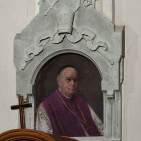 Zdjęcie nr 1: Epitafium w kształcie aediculi z półkolistą arkadą z portretem zmarłego i tablicą z inskrypcją poniżej. Arkada zwieńczona daszkiem portalowym, na którym infuła z karbowanymi taśmami i krzyżem oraz skrzyżowanymi za nią krzyżem i pastorałem. Duchowny przedstawiony w półpostaci, w trzech czwartych, w lewo. Twarz oddana realistycznie, o prostych rysach, z oczami zwróconymi na wprost, długim nosie, wyrazistych, zaciśniętych ustach, z odsłoniętą łysiną i czarną piuską na głowie. Ubrany w komżę i fioletowy mantolet. Na tablicy u dołu częściowo wypukłorzeźbiona, a częściowo ryta inskrypcja:  "D(EO) O(PTIMO) M(AXIMO) / KS(IĄDZ) JÓZEF KRZEMIEŃSKI / PRAŁAT DOM(OWY) OJCA Ś(więte)go KANONIK H(ONOROWY) WARSZAWSKI / ARCHIPREZBYTER KOŚCIOŁA N(AJŚWIĘTSZEJ) P(ANNY) MARYI / URODZONY w KRAKOWIE 1835 ZMARŁ w r(oku) 1912 / B(YŁY) PROBOSZCZ W MORAWICY. / PROSI O WESTCHNIENIE DO BOGA!"  