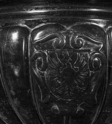 Zdjęcie nr 7: Podstawa okrągła, dwustopniowa z prostopadłościenną górną częścią, z trzonem w typie gruszkowatym z wałkiem w górnej części, podtrzymującym czarę w formie spłaszczonej kuli z puklami. Na czarze tarcza herbowa ujęta wolutami z godłem herbu Szaszor lub Orla. Pokrywa drewniana, w kształcie smukłej półkopuły o powierzchni pokrytej srebrzonymi łuskami, obwiedzionej koroną, podzielona żebrami z żabkami i zwieńczona koroną. Nad kopułą sześcioboczna wieżyczka ujęta wolnostojącymi pinaklami. Jej ścianki zakończone trójkątnie z ornamentalnymi grzebieniami, wypełnione wnękami z postaciami aniołów. Nad wieżyczką figura św. Jana Chrzciciela, ubranego w wielbłądzią skórę i płaszcz przerzucony na prawym ramieniu. W prawej dłoni podtrzymuje baranka, w lewej trzyma osadzony na długim trzpieniu krzyż. Na wewnętrznej stronie pokrywy tabliczka z inskrypcją: „CURA ET IMPENSIS / JOSEPHI PAJĄCZEWSKI / CURATI MORAVICEAEN ET / DECANI CZERNICHOVIEN A(NNO) D(OMINI) 1904 A(D) M(AIOREM) D(EI) G(LORIAM)”.        