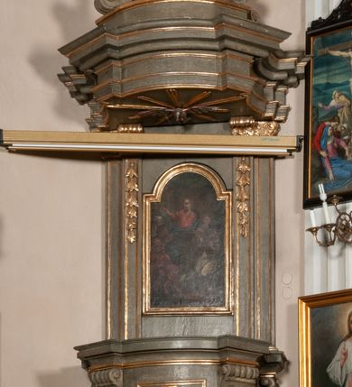 Zdjęcie nr 15: Kosz ambony na rzucie czworoboku, o bokach lekko wypukłych, wsparty na piramidalnym cokole z szyszką ujętą liśćmi. Kosz podzielony szerokimi, kanelowanymi spływami i zwieńczony gzymsem. Na ściance frontowej płaskorzeźbiona figura Chrystusa błogosławiącego trzymany w ręku bochenek chleba. Zaplecek flankowany profilowanymi listwami z kampanulami zakończonymi ulistnionymi konsolkami, pośrodku obraz w kształcie stojącego prostokąta zamkniętego łukiem półkolistym, nadwieszonym z przedstawieniem Jezusa wśród mędrców. Baldachim powielający rzut kosza, profilowany, ujęty impostami, zwieńczony czterema esowato wygiętymi i łączącymi się górą kabłąkami. Na podniebieniu baldachimu gołębica Ducha Świętego ,a tle promieni. Na nich figura Chrystusa Zmartwychwstałego, ukazanego w całej postaci, w kontrapoście, z płaszczem na plecach osłaniającym biodro. Prawą rękę unosi w geście błogosławieństwa, w lewej trzyma chorągiew. 