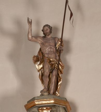 Zdjęcie nr 19: Kosz ambony na rzucie czworoboku, o bokach lekko wypukłych, wsparty na piramidalnym cokole z szyszką ujętą liśćmi. Kosz podzielony szerokimi, kanelowanymi spływami i zwieńczony gzymsem. Na ściance frontowej płaskorzeźbiona figura Chrystusa błogosławiącego trzymany w ręku bochenek chleba. Zaplecek flankowany profilowanymi listwami z kampanulami zakończonymi ulistnionymi konsolkami, pośrodku obraz w kształcie stojącego prostokąta zamkniętego łukiem półkolistym, nadwieszonym z przedstawieniem Jezusa wśród mędrców. Baldachim powielający rzut kosza, profilowany, ujęty impostami, zwieńczony czterema esowato wygiętymi i łączącymi się górą kabłąkami. Na podniebieniu baldachimu gołębica Ducha Świętego ,a tle promieni. Na nich figura Chrystusa Zmartwychwstałego, ukazanego w całej postaci, w kontrapoście, z płaszczem na plecach osłaniającym biodro. Prawą rękę unosi w geście błogosławieństwa, w lewej trzyma chorągiew. 