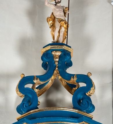 Zdjęcie nr 11: Kosz ambony na rzucie czworoboku, o bokach lekko wypukłych, wsparty na piramidalnym cokole z szyszką ujętą liśćmi. Kosz podzielony szerokimi, kanelowanymi spływami i zwieńczony gzymsem. Na ściance frontowej płaskorzeźbiona figura Chrystusa błogosławiącego trzymany w ręku bochenek chleba. Zaplecek flankowany profilowanymi listwami z kampanulami zakończonymi ulistnionymi konsolkami, pośrodku obraz w kształcie stojącego prostokąta zamkniętego łukiem półkolistym, nadwieszonym z przedstawieniem Jezusa wśród mędrców. Baldachim powielający rzut kosza, profilowany, ujęty impostami, zwieńczony czterema esowato wygiętymi i łączącymi się górą kabłąkami. Na podniebieniu baldachimu gołębica Ducha Świętego ,a tle promieni. Na nich figura Chrystusa Zmartwychwstałego, ukazanego w całej postaci, w kontrapoście, z płaszczem na plecach osłaniającym biodro. Prawą rękę unosi w geście błogosławieństwa, w lewej trzyma chorągiew. 