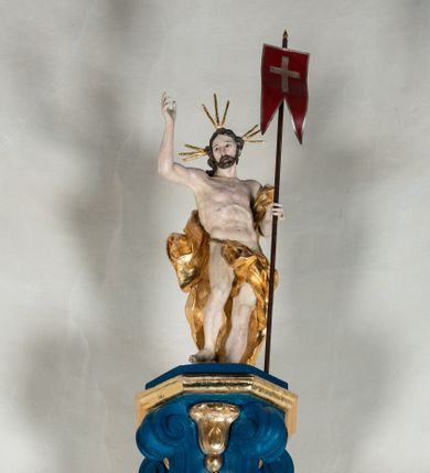 Zdjęcie nr 12: Kosz ambony na rzucie czworoboku, o bokach lekko wypukłych, wsparty na piramidalnym cokole z szyszką ujętą liśćmi. Kosz podzielony szerokimi, kanelowanymi spływami i zwieńczony gzymsem. Na ściance frontowej płaskorzeźbiona figura Chrystusa błogosławiącego trzymany w ręku bochenek chleba. Zaplecek flankowany profilowanymi listwami z kampanulami zakończonymi ulistnionymi konsolkami, pośrodku obraz w kształcie stojącego prostokąta zamkniętego łukiem półkolistym, nadwieszonym z przedstawieniem Jezusa wśród mędrców. Baldachim powielający rzut kosza, profilowany, ujęty impostami, zwieńczony czterema esowato wygiętymi i łączącymi się górą kabłąkami. Na podniebieniu baldachimu gołębica Ducha Świętego ,a tle promieni. Na nich figura Chrystusa Zmartwychwstałego, ukazanego w całej postaci, w kontrapoście, z płaszczem na plecach osłaniającym biodro. Prawą rękę unosi w geście błogosławieństwa, w lewej trzyma chorągiew. 