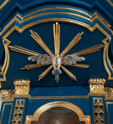 Zdjęcie nr 30: Kosz ambony na rzucie czworoboku, o bokach lekko wypukłych, wsparty na piramidalnym cokole z szyszką ujętą liśćmi. Kosz podzielony szerokimi, kanelowanymi spływami i zwieńczony gzymsem. Na ściance frontowej płaskorzeźbiona figura Chrystusa błogosławiącego trzymany w ręku bochenek chleba. Zaplecek flankowany profilowanymi listwami z kampanulami zakończonymi ulistnionymi konsolkami, pośrodku obraz w kształcie stojącego prostokąta zamkniętego łukiem półkolistym, nadwieszonym z przedstawieniem Jezusa wśród mędrców. Baldachim powielający rzut kosza, profilowany, ujęty impostami, zwieńczony czterema esowato wygiętymi i łączącymi się górą kabłąkami. Na podniebieniu baldachimu gołębica Ducha Świętego ,a tle promieni. Na nich figura Chrystusa Zmartwychwstałego, ukazanego w całej postaci, w kontrapoście, z płaszczem na plecach osłaniającym biodro. Prawą rękę unosi w geście błogosławieństwa, w lewej trzyma chorągiew. 