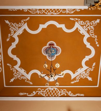 Zdjęcie nr 20: Fresk wkomponowany w arkadę zamkniętą półkoliście, w ścianie południowej prezbiterium, nad portalem do aneksu. Ukazuje siedzącą na tronie Matkę Boską z Dzieciątkiem na kolanach oraz klęczących i stojących przed nią od lewej proboszcza Józefa Krzemińskiego, rodzinę w stroju ludowym, Izabelę i Felicjana Szybalskich oraz chłopca z chorągwią w ręku. 