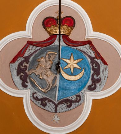 Zdjęcie nr 19: Fresk wkomponowany w arkadę zamkniętą półkoliście, w ścianie południowej prezbiterium, nad portalem do aneksu. Ukazuje siedzącą na tronie Matkę Boską z Dzieciątkiem na kolanach oraz klęczących i stojących przed nią od lewej proboszcza Józefa Krzemińskiego, rodzinę w stroju ludowym, Izabelę i Felicjana Szybalskich oraz chłopca z chorągwią w ręku. 