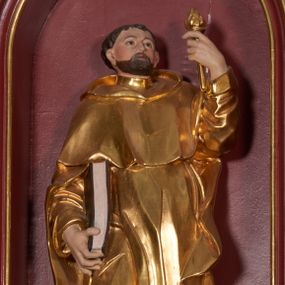 Zdjęcie nr 1: Rzeźba ścięta z tyłu, zapewne wydrążona. Postać ujęta w lekkim kontrapoście, z prawą ręką trzymająca zamkniętą księgę, a w lewej trzymającą pochodnię. Jego głowa jest zwrócona w lewo i lekko uniesiona. Twarz okolona krótkim zarostem, włosy krótkie, brązowe. Święty jest ubrany w habit dominikański, mocno fałdowany w dolnej części z widocznymi brązowymi butami oraz płaszcz z kapturem. U jego stóp leży pies. Figura polichromowana naturalistycznie w partiach ciała, habit złocony, pies srebrzony, oprawa księgi pomalowana na kolor brązowy. 