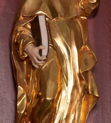 Zdjęcie nr 3: Rzeźba ścięta z tyłu, zapewne wydrążona. Postać ujęta w lekkim kontrapoście, z prawą ręką trzymająca zamkniętą księgę, a w lewej trzymającą pochodnię. Jego głowa jest zwrócona w lewo i lekko uniesiona. Twarz okolona krótkim zarostem, włosy krótkie, brązowe. Święty jest ubrany w habit dominikański, mocno fałdowany w dolnej części z widocznymi brązowymi butami oraz płaszcz z kapturem. U jego stóp leży pies. Figura polichromowana naturalistycznie w partiach ciała, habit złocony, pies srebrzony, oprawa księgi pomalowana na kolor brązowy. 