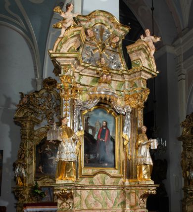 Zdjęcie nr 1: Ołtarz drewniany, prostopadłościenny z kamienną mensą, z kamiennym portatylem. Antepedium drewniane ujęte marmoryzowaną ramą z karbowanym profilem. W polu owalny medalion z przedstawieniem świętego z zakonu Marków, ujętym wicią akantową przeplatana z kwiatową. Nastawa ołtarzowa architektoniczna, jednoosiowa, jednokondygnacyjna ze zwieńczeniem na cokole.  Retabulum flankowane parą zdwojonych półfilarów zakończonych konsolami,  dźwigających pełne belkowanie oraz fragmenty przerwanego, półkolistego przyczółka z siedzącymi puttami. Na tle pilastrów, na konsolach ustawione figury dwóch świętych. Trzony pilastrów dekorowane kampanulami. W polu środkowym wnęka w formie stojącego prostokąta zamkniętego łukiem segmentowym nadwieszonego z uskokiem ujęta profilowaną ramą, z obrazem Wskrzeszenie Łazarza, w osobnej ramie. Nad wnęką baldachim dekorowany lambrekinem, z podwieszoną tkaniną po dwóch stronach, lamowaną frędzlą. Nam baldachimem kartusz z uskrzydlonymi główkami anielskimi i zwieńczony koroną. Zwieńczenie w formie zbliżonej do trapezu o wklęsłych bokach zamknięte falistym gzymsem, dekorowanym kampanulami. W polu gorejące serce przebite mieczem, w otoku z obłoków i uskrzydlonych główek anielskich, w glorii promienistej.  Struktura polichromowana w sposób imitujący marmoryzację w kolorze beżowo-zielonym. Ornamentyka i profile złocone, detal i zwieńczenie srebrzone.